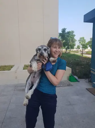 A woman cuddling her dog outside her home.