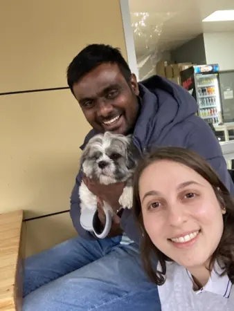 A couple smiling beside their dog.